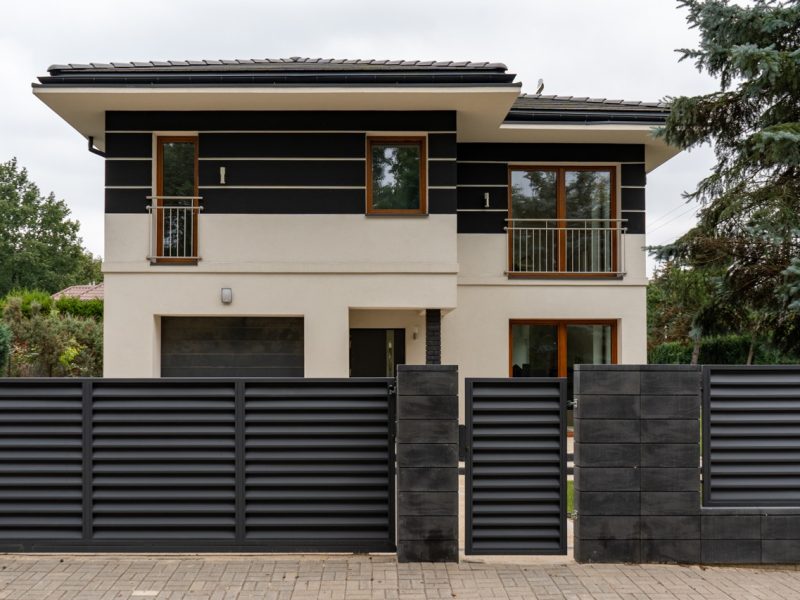 Ultra modern house: bold architectural design, contrasting facade, large windows. Dominant dark slat fence ensures high security, defining this contemporary home's private territory.